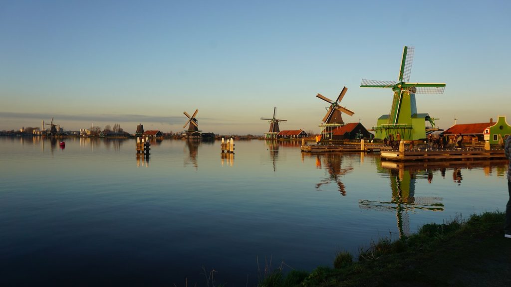 Zaanse Schans szélmalmok csatornával és zöld mezőkkel.